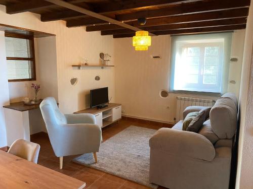 a living room with a couch and chairs and a television at Apartamentos El Campo in Castropol