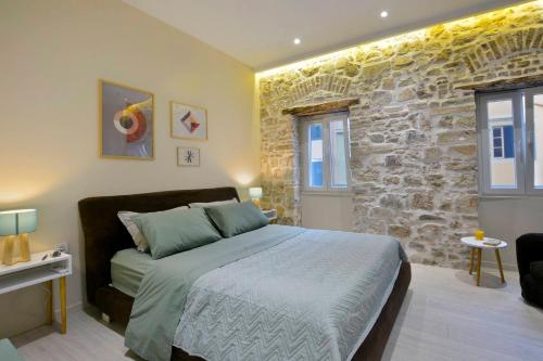 um quarto com uma cama e uma parede de pedra em Beau Maison em Corfu Town