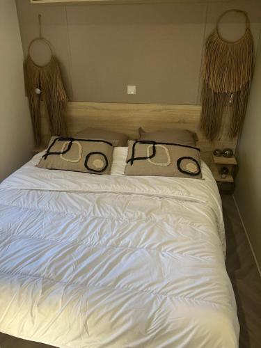 Una cama blanca con dos almohadas encima. en mobhilhome saint brevin en LʼErmitage