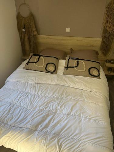 un letto bianco con due cuscini sopra di mobhilhome saint brevin a LʼErmitage