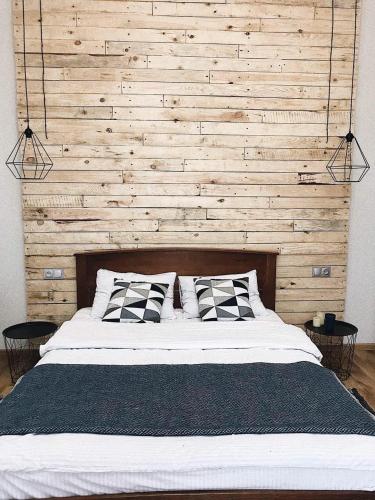 a bedroom with a large bed with a wooden wall at Apart27 in Lviv