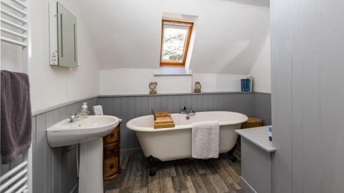 ein Badezimmer mit einer weißen Badewanne und einem Waschbecken in der Unterkunft The Ferry House Cottage in Aberfeldy