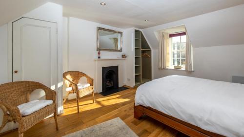 a white bedroom with a bed and a fireplace at The Ferry House Cottage in Aberfeldy