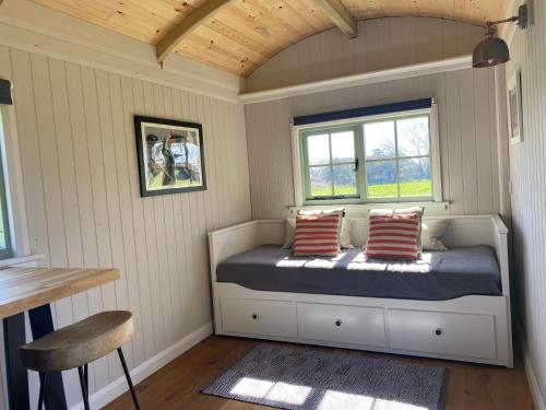 a bedroom with a bed with two pillows and a window at The Witterings Shepherds’ Hut in West Wittering