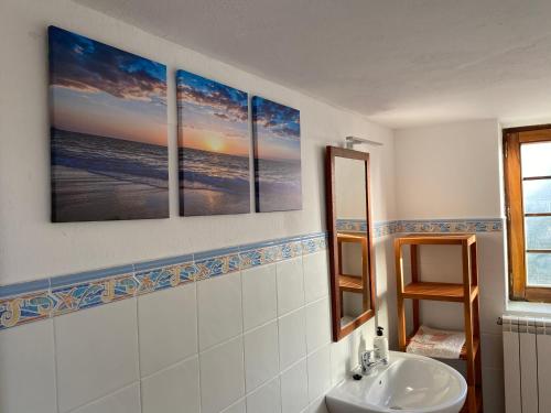baño con 3 pinturas en la pared y lavamanos en Apartamentos El Campo, en Castropol