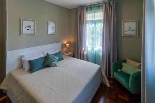 een slaapkamer met een bed en een groene stoel bij Blue House in Ponta do Sol