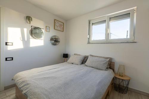 a white bedroom with a bed and a window at LaraBella Salt fields view studio in Portorož