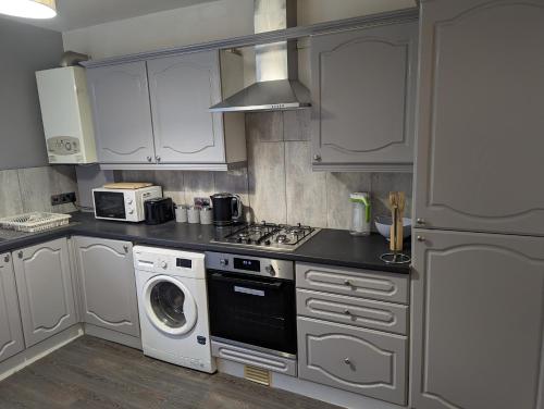 a kitchen with a stove top oven next to a washing machine at Station Apartments in Ashton in Makerfield