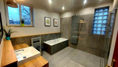La salle de bains est pourvue d'une baignoire, d'un lavabo et d'une douche. dans l'établissement METRO Pokoje & Apartamenty, à Sopot