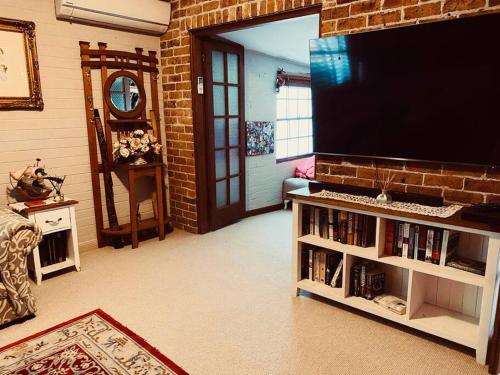 a living room with a flat screen tv on a brick wall at Paradise Lodge - Blue Mountains Wonderland in Linden