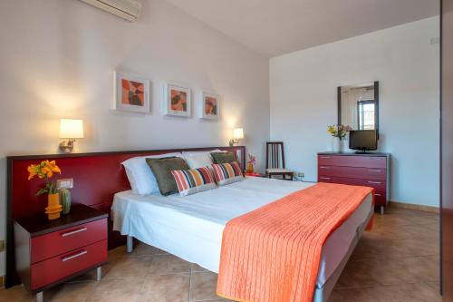 a bedroom with a large bed with a orange blanket on it at LE TERRAZZE apartments in Alghero