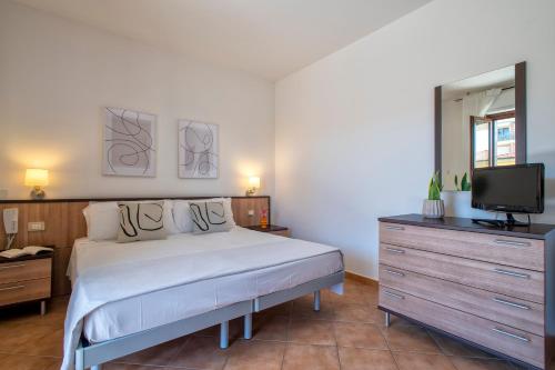 a bedroom with a bed and a dresser with a television at LE TERRAZZE apartments in Alghero