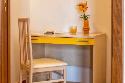 a yellow desk with a chair and a book at LE TERRAZZE apartments in Alghero