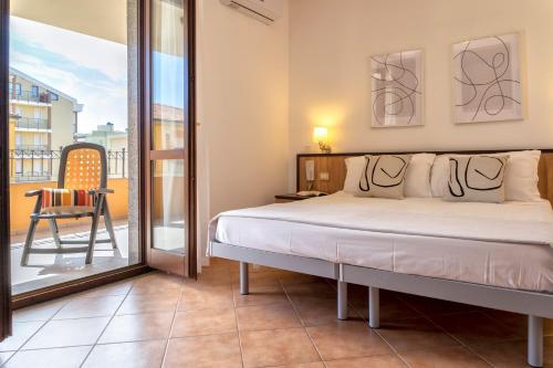a bedroom with a bed and a balcony with a chair at LE TERRAZZE apartments in Alghero