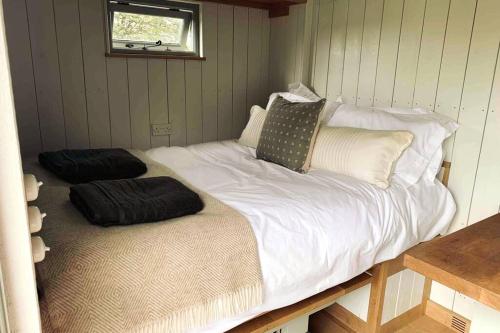 a large white bed with pillows on it in a room at The Hut - A Shepherd's Hut on our family farm in Warwickshire in Evesham