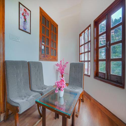 a living room with three chairs and a table with flowers on it at Pax Hotel Ark 150 meters from Mall Road in Dalhousie