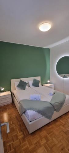 a bedroom with a white bed with a green wall at Al Nido Della Stazione in Lugano