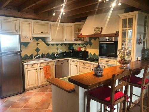 uma cozinha com um frigorífico de aço inoxidável e uma mesa em Gîte des Contes em Madiran