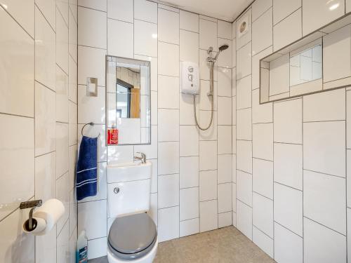a white tiled bathroom with a toilet and a shower at Mayton Lodge in Fordwich