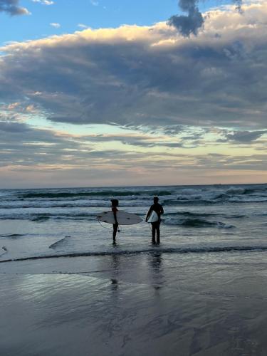 two people standing on the beach with their surfboards at Tombo Beach in Guarujá