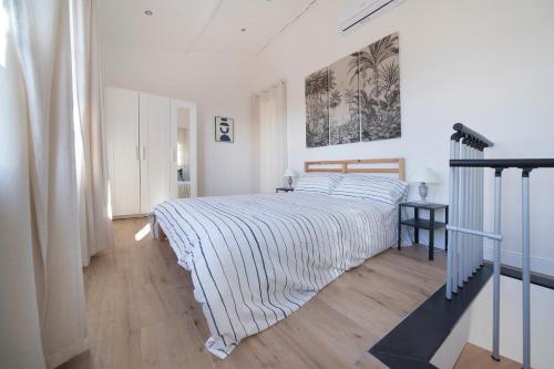 - une chambre blanche avec un lit et une couverture rayée dans l'établissement Incantevole Veranda Panoramica, à Albenga