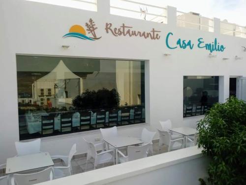 a restaurant with white chairs and tables and a sign at HOSTAL CASA EMILIO in Almería