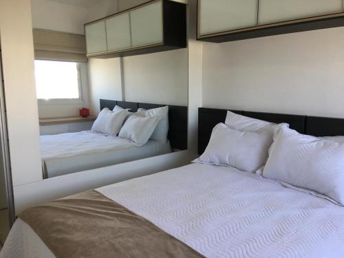 a bedroom with two beds with white pillows at Apartamento Bora Bora Resort in Rio de Janeiro