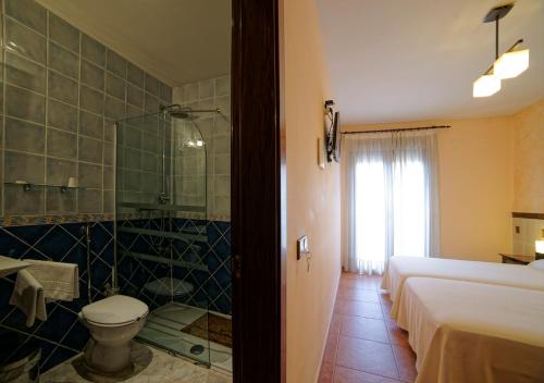 a hotel room with a bathroom with a toilet and a shower at Hostal Rural El Tejar in Layos