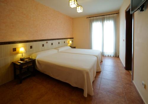 um quarto de hotel com duas camas e uma janela em Hostal Rural El Tejar em Layos