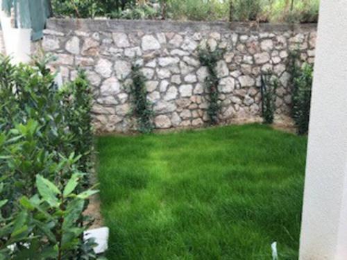 een stenen muur met een tuin met groen gras bij Splendide studio, 10' a pied de Monaco + parking in Beausoleil