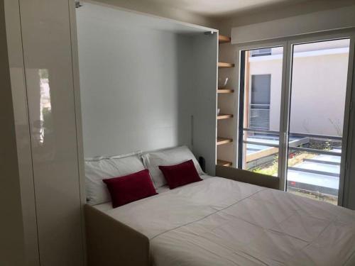 une chambre avec un grand lit avec deux oreillers rouges dans l'établissement Splendide studio, 10' a pied de Monaco + parking, à Beausoleil