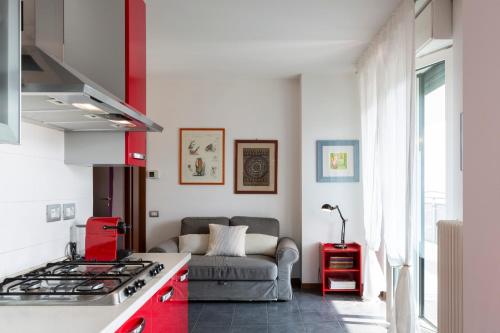 a kitchen with red cabinets and a couch in a room at Sky Home Santa Giulia in Milan