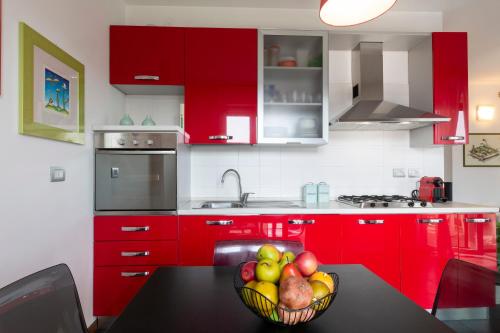 a kitchen with red cabinets and a bowl of fruit on a table at Sky Home Santa Giulia in Milan