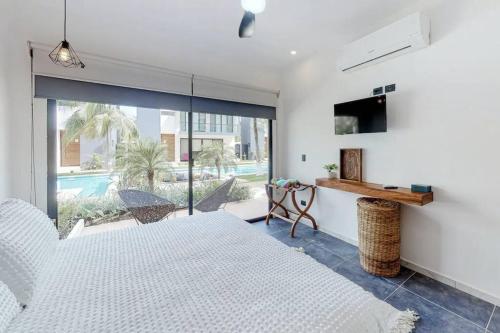 a bedroom with a white bed and a sliding glass door at Contemporary poolside Condo, Wi-Fi - Paraiso Kaanal 101 in Tulum