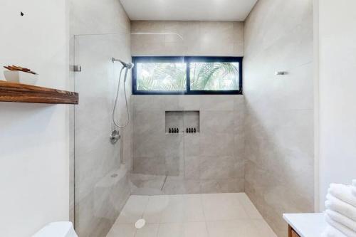 a white bathroom with a shower and a window at Contemporary poolside Condo, Wi-Fi - Paraiso Kaanal 101 in Tulum