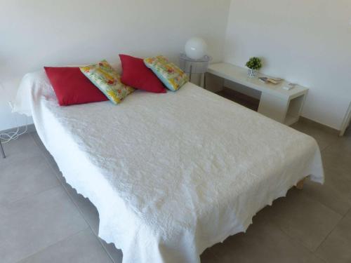 - un lit blanc avec deux oreillers rouges et une table dans l'établissement Appartement Le Lavandou, 3 pièces, 4 personnes - FR-1-308-49, au Lavandou
