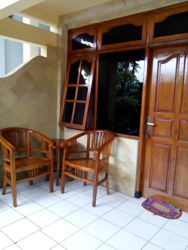 two wooden chairs sitting in front of a door at Hotel Dupa in Lovina