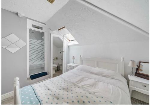 a white bedroom with a bed and a mirror at Hardwick Flat in Barnstaple