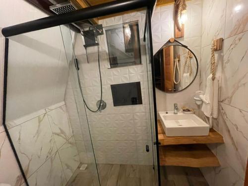 La salle de bains est pourvue d'une douche et d'un lavabo. dans l'établissement Pousada Recanto da Neve, à Urubici