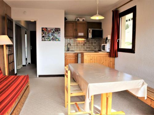 Una cocina con una mesa y un refrigerador blanco. en Auris en Oisans - Appartement 3 pièces cabine - 6 couchages au pied des pistes - FR-1-297-77, en Auris