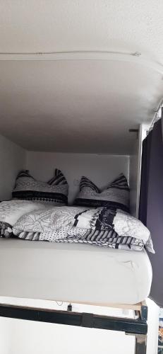 a white bed with black and white pillows on it at Einzimmerwohnung am Lechweg in Wangle