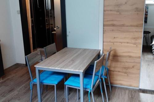 a wooden table with blue chairs in a room at Einzimmerwohnung am Lechweg in Wangle