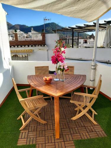 una mesa de madera y sillas en un patio con flores en El Molinillo en Ojén