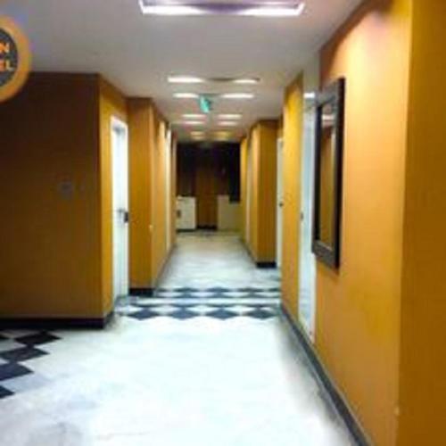 a hallway with yellow walls and a black and white floor at Hotel Sky Inn in Rawalpindi