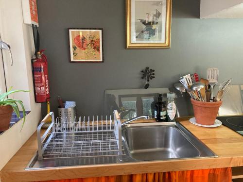 un fregadero de cocina con un estante de platos en una encimera en Unique Artists studio with a private garden., en Pewsey