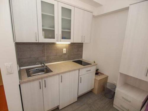 uma pequena cozinha com armários brancos e um lavatório em Apartman Nikolić 1 em Makarska