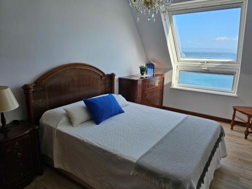 um quarto com uma cama com almofadas azuis e uma janela em Ático en primera línea de playa em Ribeira