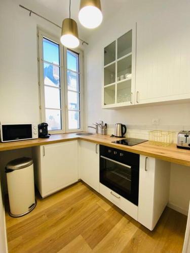 une cuisine avec des armoires blanches et un four noir dans l'établissement Les Deux Anges, à Rouen