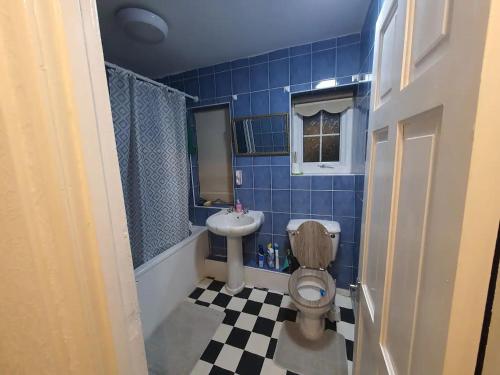 a blue tiled bathroom with a toilet and a sink at Spacious Double Bedroom Greater Manchester in Middleton