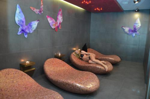 a room with a woman laying in a room with butterflies at Hotel Azalia & Spa in Niepołomice